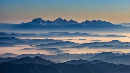 Obraz premium Majestic mountain range under misty sky at sunrise illuminating the horizon