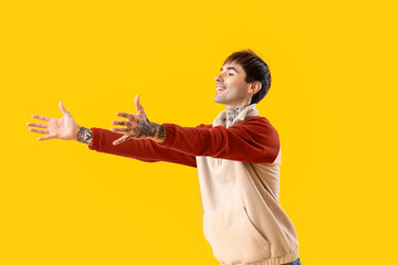 Young man opening arms for hug on yellow background