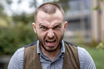 Fototapeta premium Close-up portrait of an angry man with a beard. His eyes are wide open and his mouth is slightly open.