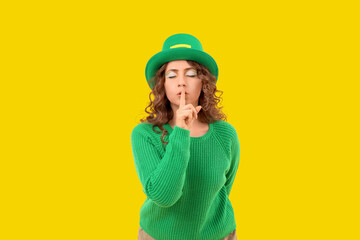Woman in green clothes showing silence gesture on yellow background. St. Patrick's Day