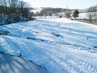 A serene winter landscape covered in fresh snow, showcasing a tranquil scene with trees and open...