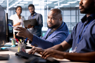 Teamworking engineers in data center using diagnostic tools and system monitoring software to...