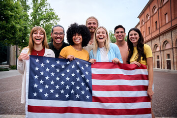 Multiracial group of friends holding the American flag with pride, celebrating Independence Day...