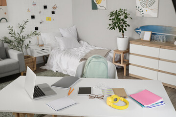 Student's table with laptop and copybooks in bedroom