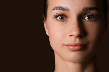 Young woman with beautiful eyebrows on dark background, closeup