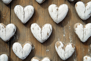 Obraz premium Decorative white wooden hearts arranged on a rustic wooden background create a charming and inviting atmosphere