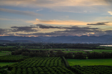 Vibrant landscape at dusk with rolling hills and lush green fields in a serene countryside