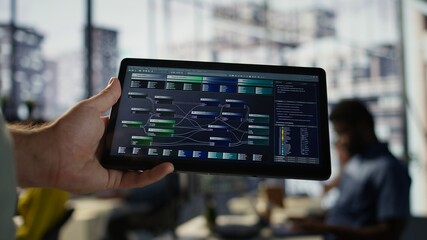 Software engineer using tablet to design algorithms that enable machines to learn from data. Close...