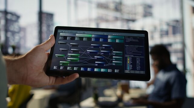 Software engineer using tablet to design algorithms that enable machines to learn from data. Close up of admin in office training and deploying large scale deep learning models with device, camera B