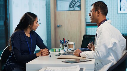 Indian general practitioner and patient engage in a medical consultation with diagnostic tools and x ray text results for scan interpretation. Showcasing healthcare practices and research. Camera A.