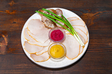 Sliced cold cuts with sauces served on a wooden table Savory vegetable pie served with fresh garnishes on a white plate