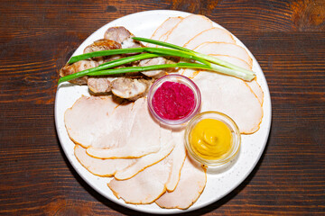Plate of sliced meats with condiments and green onions at a casual setting Savory vegetable pie served with fresh garnishes on a white plate