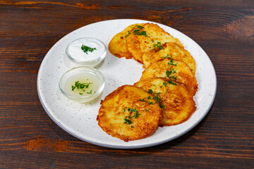 Delicious potato pancakes served with cream and sauce Savory vegetable pie served with fresh garnishes on a white plate