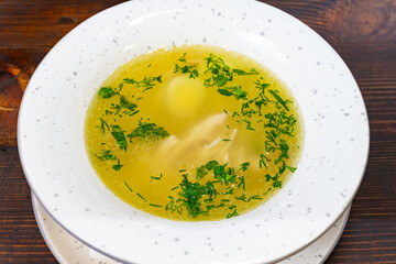 Homemade chicken broth with herbs and a soft-boiled egg served in bowl Savory vegetable pie served with fresh garnishes on a white plate