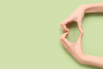 Female hands showing heart gesture on green background