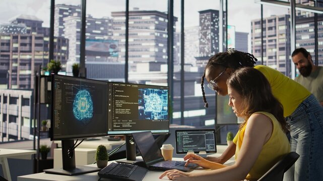 Admin assisted by coworker while utilizing cloud computing resources to train large scale machine learning models. Woman and colleague monitoring AI company systems using computer, camera B