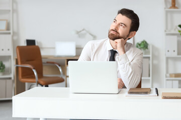 Young businessman looking upwards at table in office