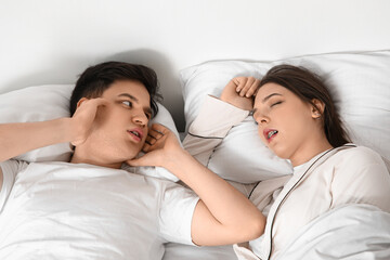 Young annoyed man suffering from loud snoring of his wife at home