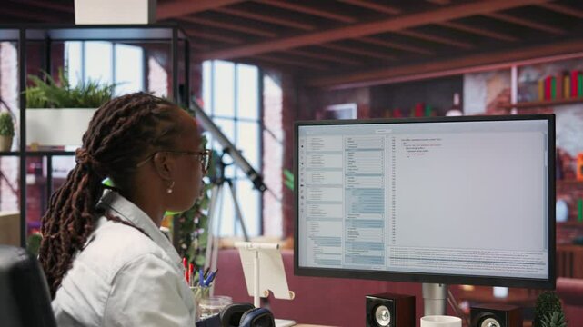 System administrator types code into PC, developing software, entering commands. IT professional at home fixing errors in application, implementing new features, listening music, camera B