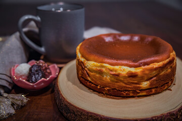 Basque cheesecake with a cup of tea and a few chocolates on a dark wooden table