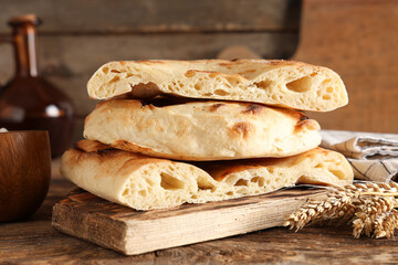 Board with stack of tasty lavash pieces and wheat spikelets on wooden background