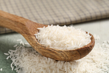 Wooden spoon with raw rice on grunge background