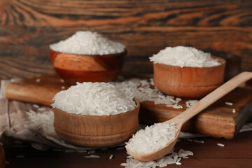 Spoon and bowls of raw rice on table against wooden background. Closeup