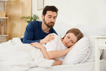 Young man apologizing to his wife in bedroom