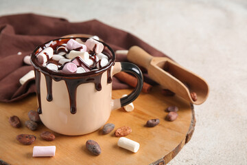 Cup of hot chocolate with marshmallows and cocoa beans on white grunge background