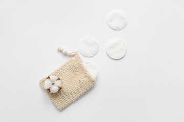 Bag with cosmetic pads and cotton flower on light background