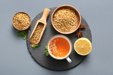 Cup of hot buckwheat tea with mint leaves, anise stars and lemon on grey background