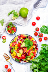 Corn salad with red beans, avocado, tomatoes, onion and cilantro. White background, top view