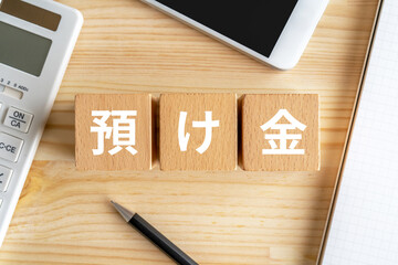 預け金と書かれたブロック、電卓、スマホ