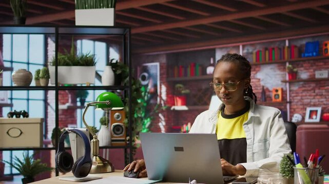 Portrait of happy teleworker using laptop in home office to write emails. Joyful remote worker typing on notebook, composing documents in order to deliver finalized project paperwork, camera A