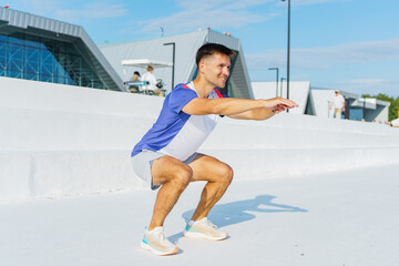 Man performs squats outdoors in modern urban setting during bright sunny day