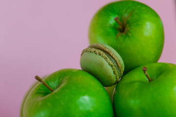Apple sweet pastries and desserts. Macarons with apple aroma and taste.Green macaroons and green apples on a pink background.French pastries.Fruit pastries with apple aroma and cream. 