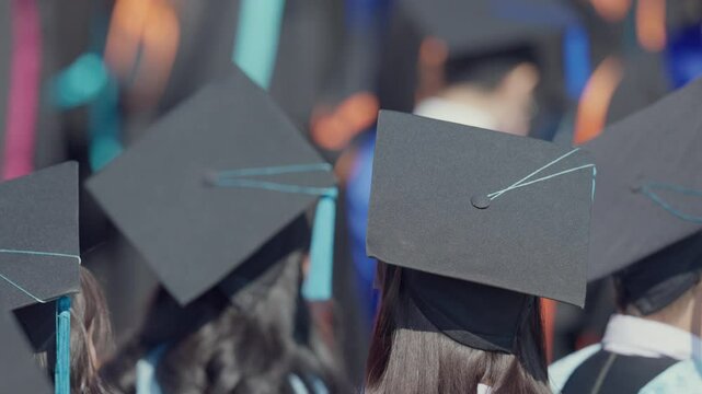 A group of people wearing graduation caps and gowns. Scene is celebratory and proud