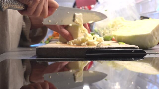 Stockholm, Sweden A domestic cook cuts cabbage for a s stir fry on a kitchen countertop with a sharp knife. 