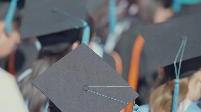 A group of people wearing graduation caps and gowns. Scene is celebratory and proud