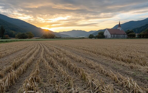 Golden sunlight spills over harvested fields as a quaint church stands against the backdrop of rolling hills. The tranquil scene captures the essence of countryside life at dusk