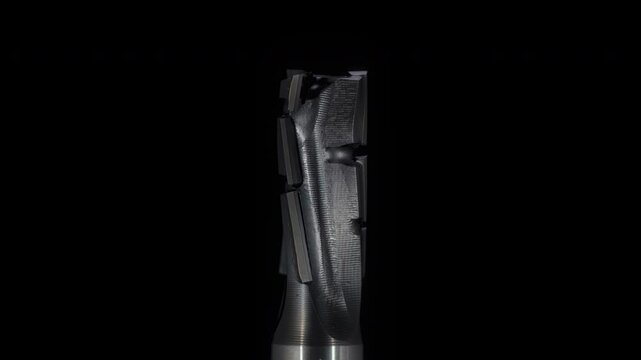 Macro, metal end mill rotates around the axis on a black background