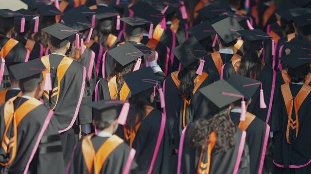 A large group of people wearing graduation caps and gowns. Scene is celebratory and proud