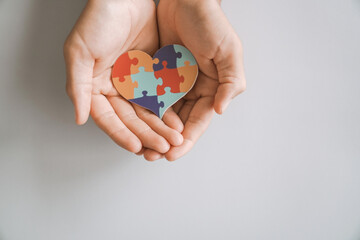 hands holding jigsaw puzzle heart shape, Autism awareness,Autism spectrum disorder family support concept, World Autism Awareness Day
