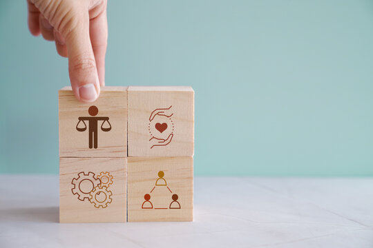 Hand holding wooden block with Ethical icons, business ethics and corporate compliance concept
