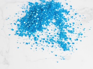 Obraz premium A collection of glinting blue particles scattered on a white marble surface, radiant shards, gemstone shards