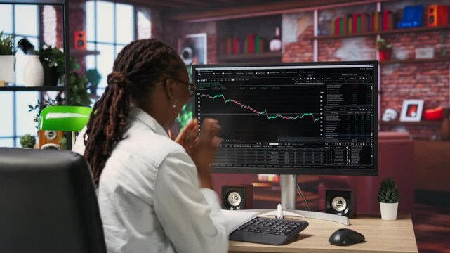 Excited day trader gaining money by selling stocks after browsing through documents to learn how to maximize profits. Thrilled investor celebrating financial gains earned from stock exchange, camera B