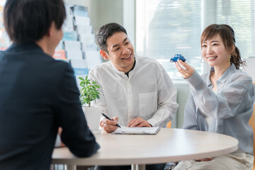 ショールーム・商談スペースで話を聞く夫婦と接客するビジネスマン
