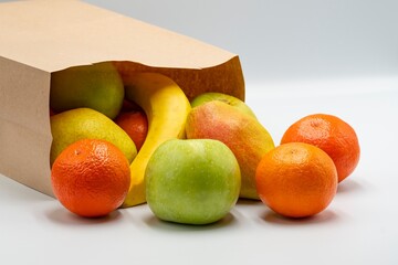 Fresh ripe fruits in paper bags on white background.