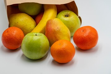 Fresh ripe fruits in paper bags on white background.