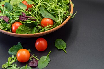 Healthy eating. Fresh salad with spinach, tomatoes and arugula in a plate on a gray background.